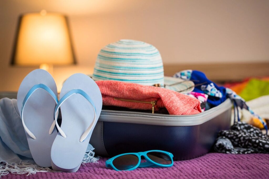 A suitcase with sunglasses and hat sitting on it.