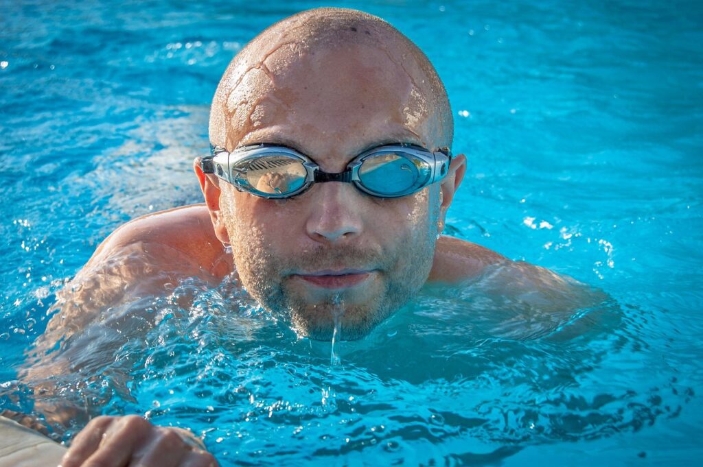 A man swimming in the pool with goggles on.